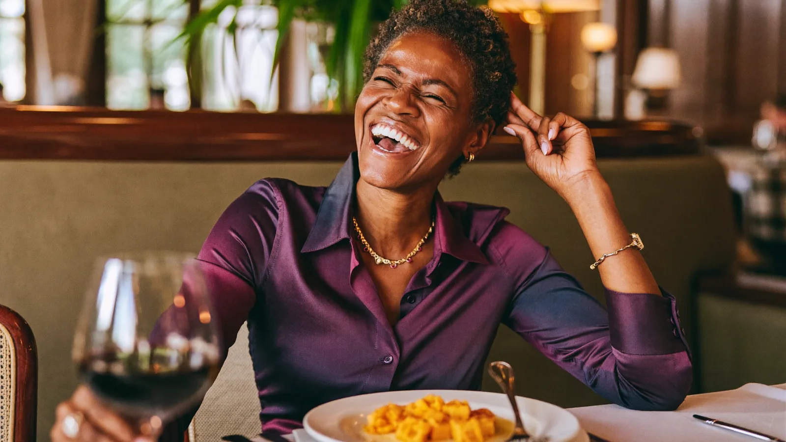 Woman laughing with a glass of wine at lunch